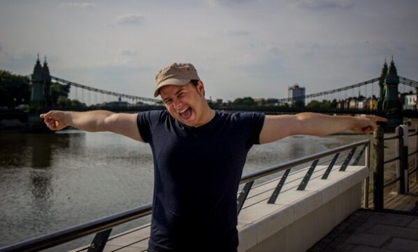 A man stretching is arms across a bridge in the background