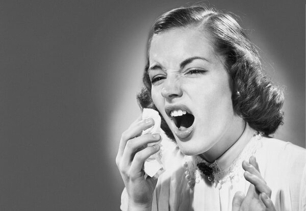 A woman about to sneeze holding a tissue